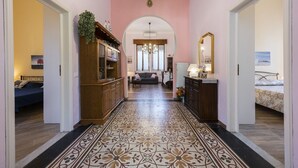 A hallway with a patterned floor, wooden cabinets, a mirror, and a chandelier. - Villa Perondi by MMega (Camaiore)