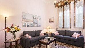 A living room with a sofa, a coffee table, a lamp, a vase with flowers, and artwork on the wall. - Villa Perondi by MMega (Camaiore)
