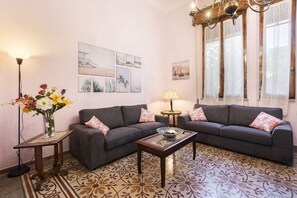 A living room with a sofa, a coffee table, a lamp, a vase with flowers, and artwork on the wall.