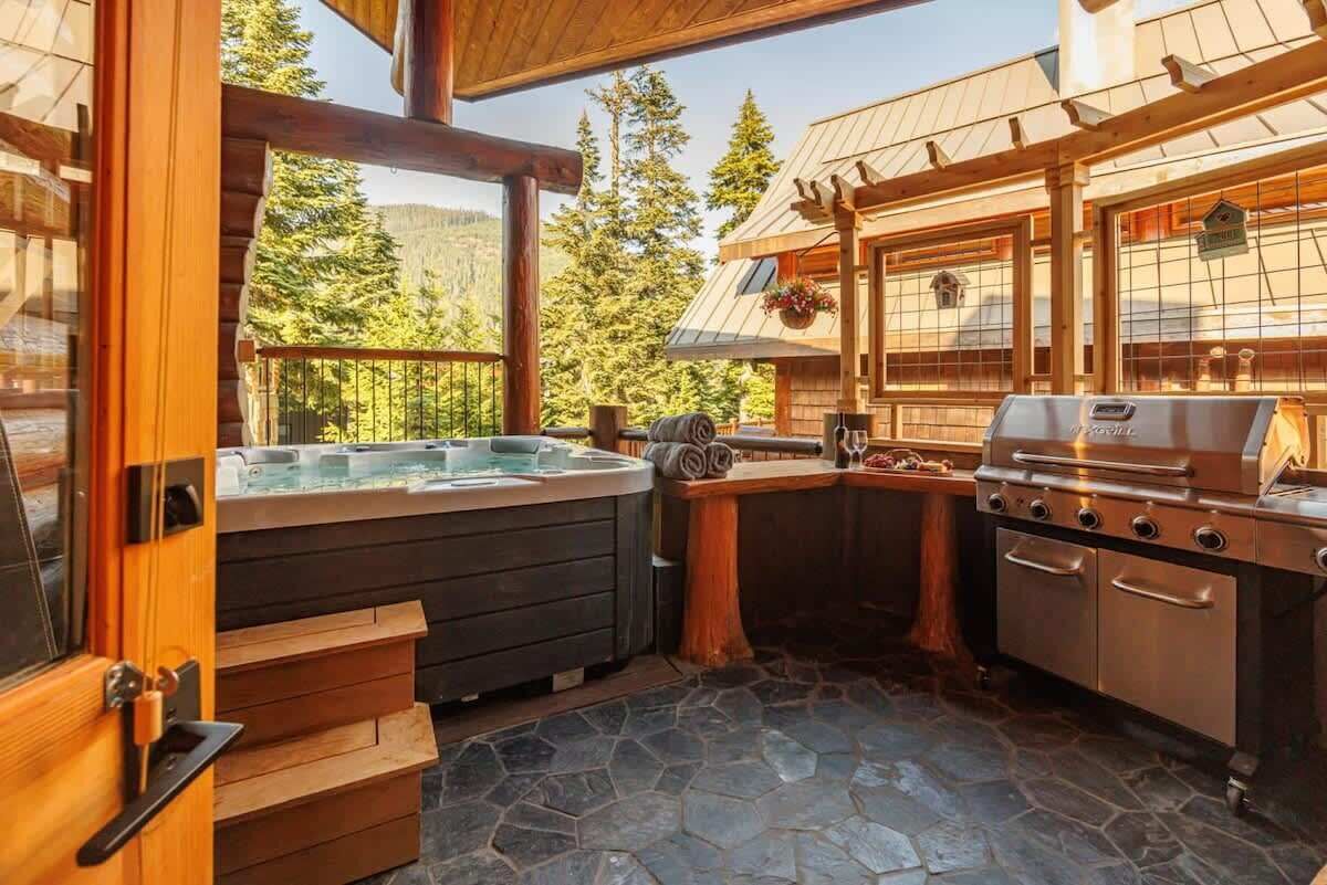 Eine Holzhütte mit Whirlpool, Grill und Steinboden.