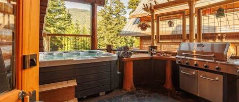 Eine Holzhütte mit Whirlpool, Grill und Steinboden.