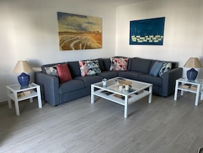 A modern living room with a grey sofa, white coffee tables, and two side tables with lamps.
