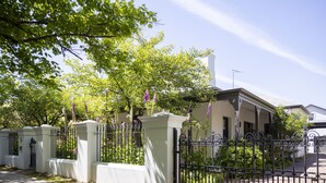 A gated residential area with a white building, a covered porch, and a clear sky.