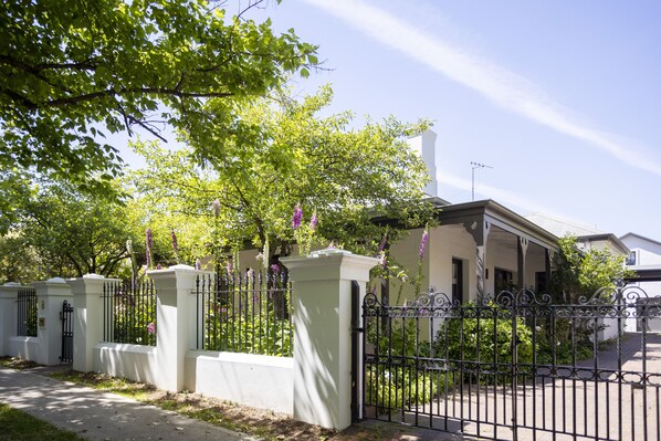 A gated residential area with a white building, a covered porch, and a clear sky.