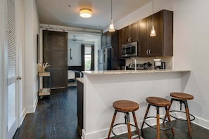 A modern kitchen with dark wood cabinets, stainless steel appliances, and a bar area with stools.