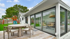 A modern patio with a wooden deck, a round table, and chairs. - 501 Managed By Brampton Park (Delray Beach)