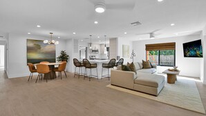 A modern apartment with a dining area, kitchen, living room, and a large window with a cityscape view. - 501 Managed By Brampton Park (Delray Beach)