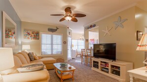 Ein Wohnzimmer mit Sofa, Couchtisch, Fernseher und Deckenventilator.