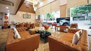A spacious lobby with leather sofas, a television, and a large window offering a view of the street.