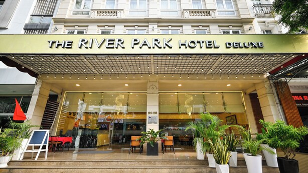 The River Park Hotel Deluxe with a prominent entrance, large windows, and potted plants in front.