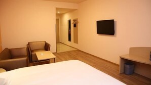 A hotel room with a bed, a desk, a chair, a TV, and a trash bin. - Grace Inn (Yutai Bus Station) (Yutai)