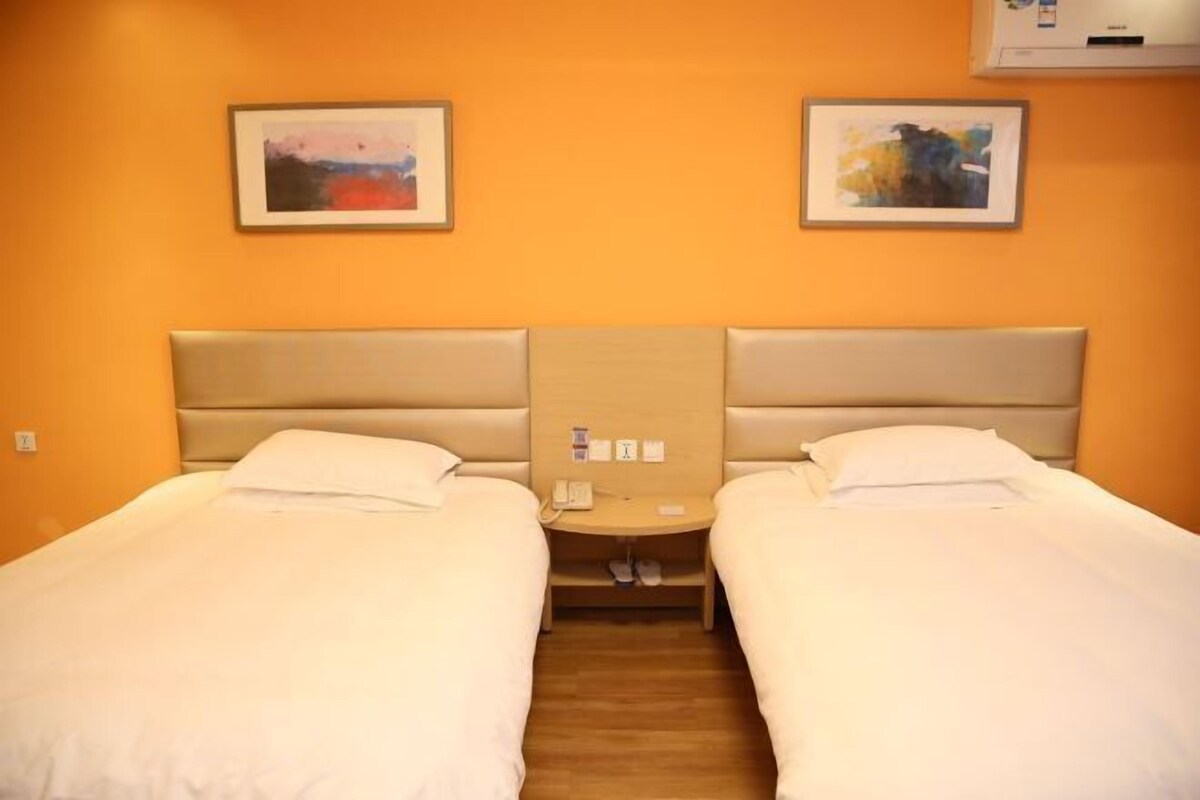 A double room with two beds, a wooden floor, and a wall-mounted air conditioner.