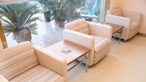 A seating area with cushioned chairs and a wooden table, a potted plant, and a view of the outside. - Grace Inn (Yutai Bus Station) (Yutai)
