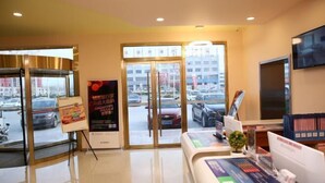 A hotel reception area with a glass door entrance, a reception desk, a television, and a view of the street outside. - Grace Inn (Yutai Bus Station) (Yutai)