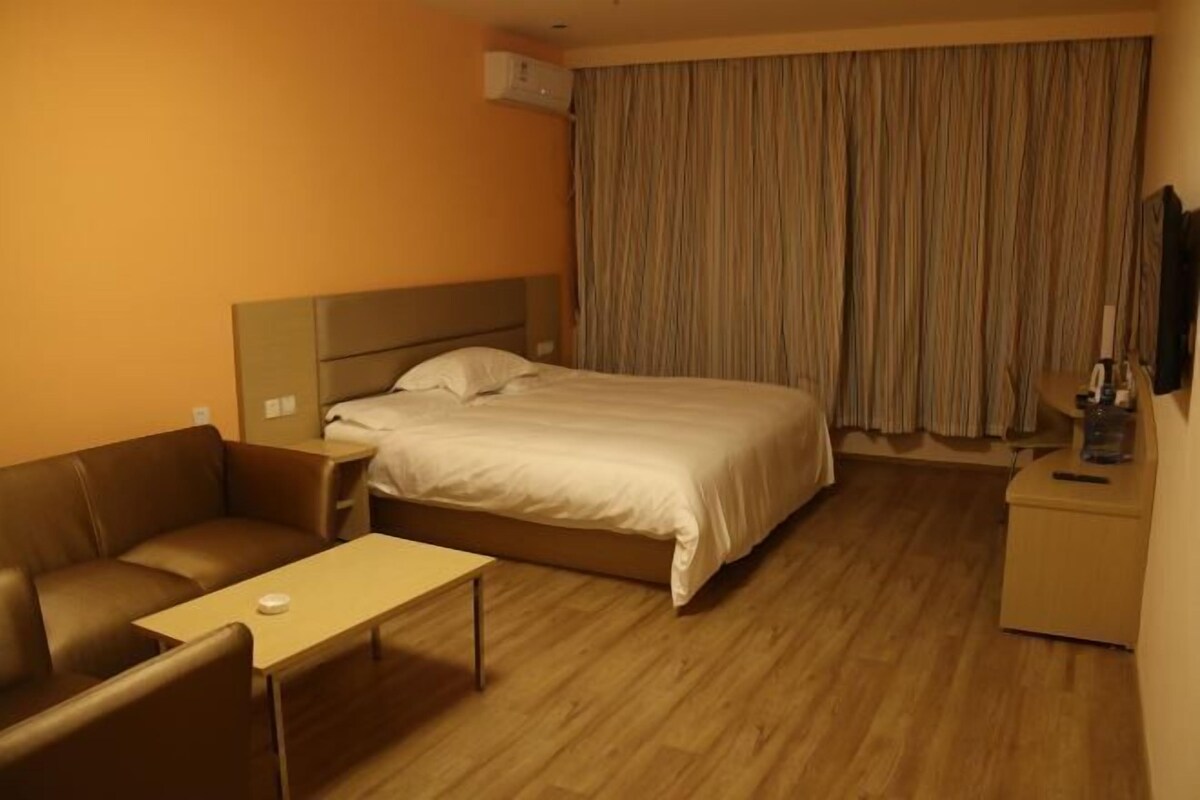 A hotel room with a bed, a sofa, a small table, and a nightstand.