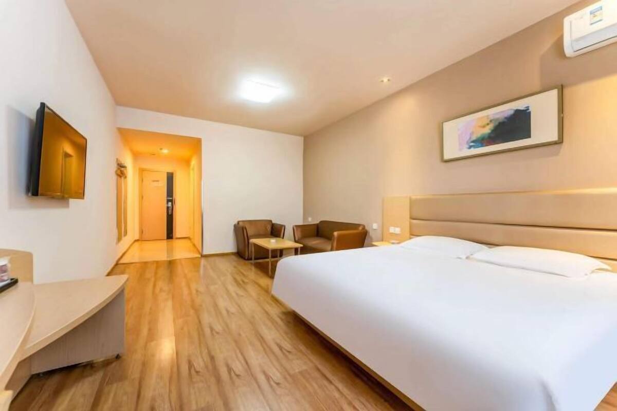 A hotel room with a large bed, a desk, two chairs, and a small table.