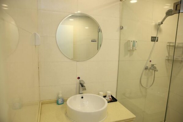 A bathroom with a round mirror, a sink, and a glass-enclosed shower area. - Grace Inn (Yutai Bus Station) (Yutai)