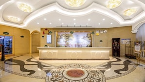 A hotel lobby with a reception desk, a mural, and a patterned floor. - Vienna Hotel (Huizhou)