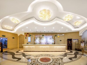 Eine Hotelhalle mit einer Rezeption, einem Wandgemälde und einem gemusterten Boden.