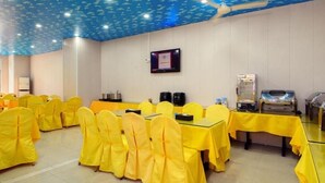 A conference room with tables and chairs, a ceiling fan, a television, and a buffet setup. - Vienna Hotel (Huizhou)