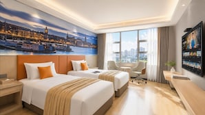 A hotel room with two beds, a desk, a chair, and a large window with a cityscape view. - Vienna Hotel (Huizhou)