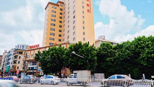 A multi-story building with a prominent sign on the facade, surrounded by other buildings and vehicles. - Vienna Hotel (Huizhou)