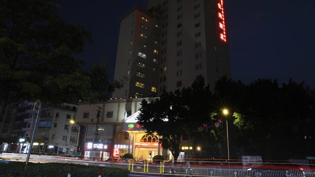 A multi-story hotel with illuminated signage, a prominent entrance, and surrounding urban infrastructure. - Vienna Hotel (Huizhou)