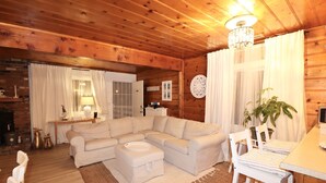 A cozy living room with a sectional sofa, a small ottoman, a dining table with chairs, and a chandelier. - Romantic Winter Escape with Mountain Views (Running Spring (Arrowbear lake area))