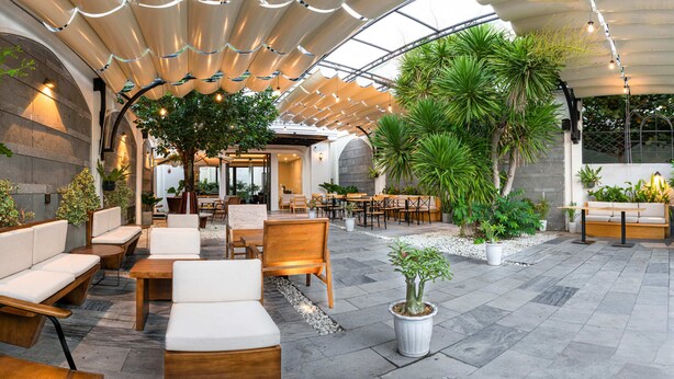 An outdoor seating area with wooden furniture and potted plants. - Le Cap Hotel & Apartment (Da Nang)