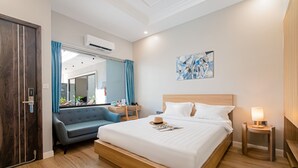 A modern hotel room with a large bed, a sofa, a desk, and a bathroom visible through a glass door. - Le Cap Hotel & Apartment (Da Nang)