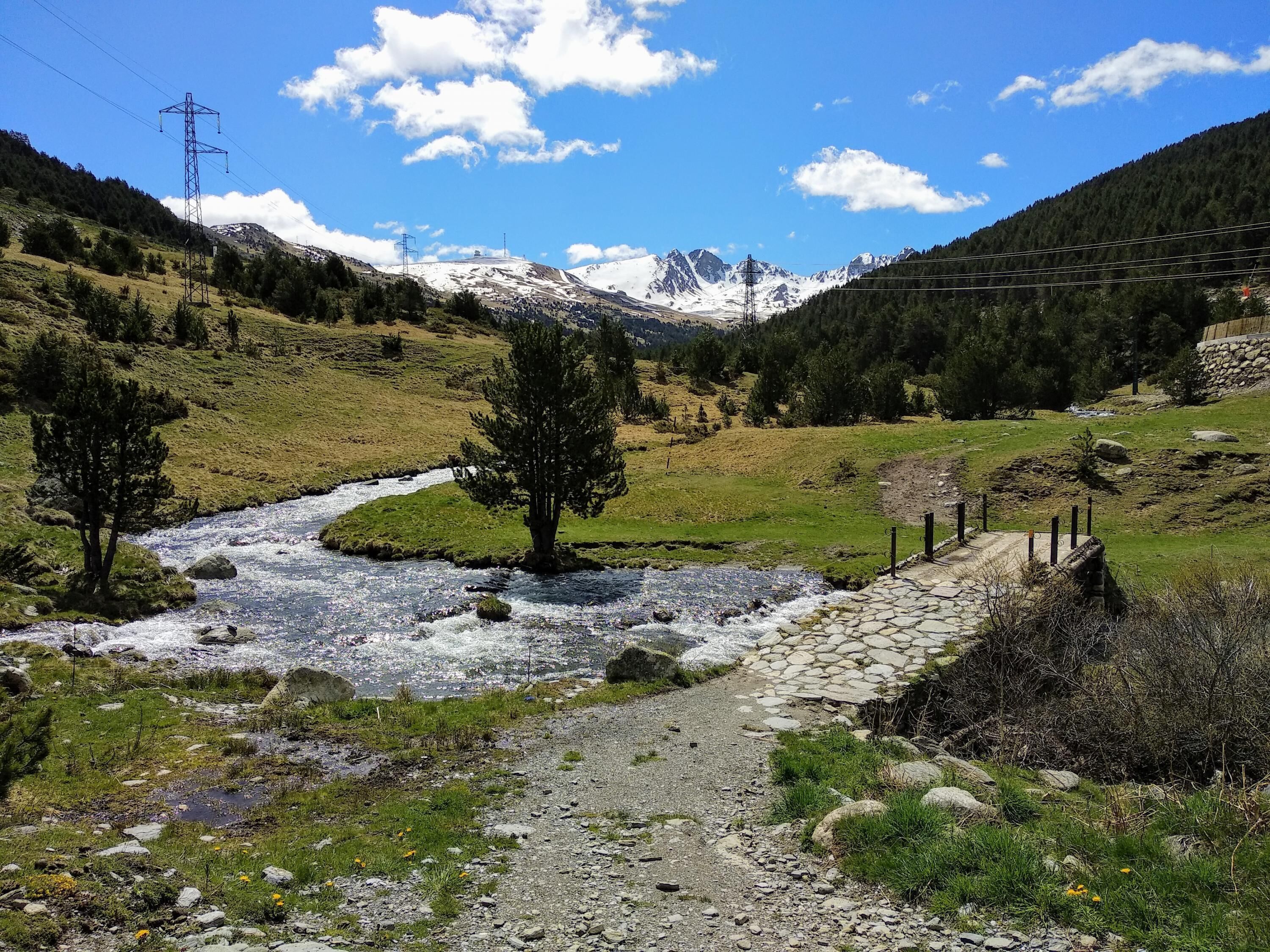 A mountainous landscape with a river, a stone path, and a fence.