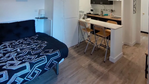 A compact living space with a bed, a kitchenette, and a dining area.
