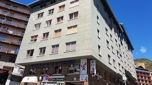 A multi-story building with a sign for 'SUPERMERCAT' on the ground floor, indicating a supermarket.
