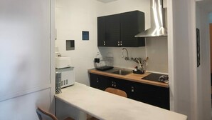 A compact kitchen with a central island, dark cabinets, and a stainless steel range hood.