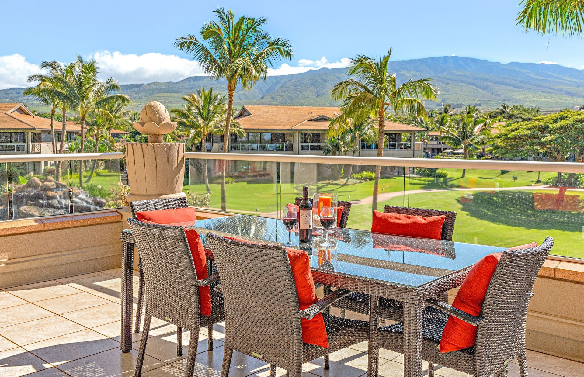 Comedor con sillas de mimbre y una mesa de vidrio, con vista a un campo de golf y montañas.