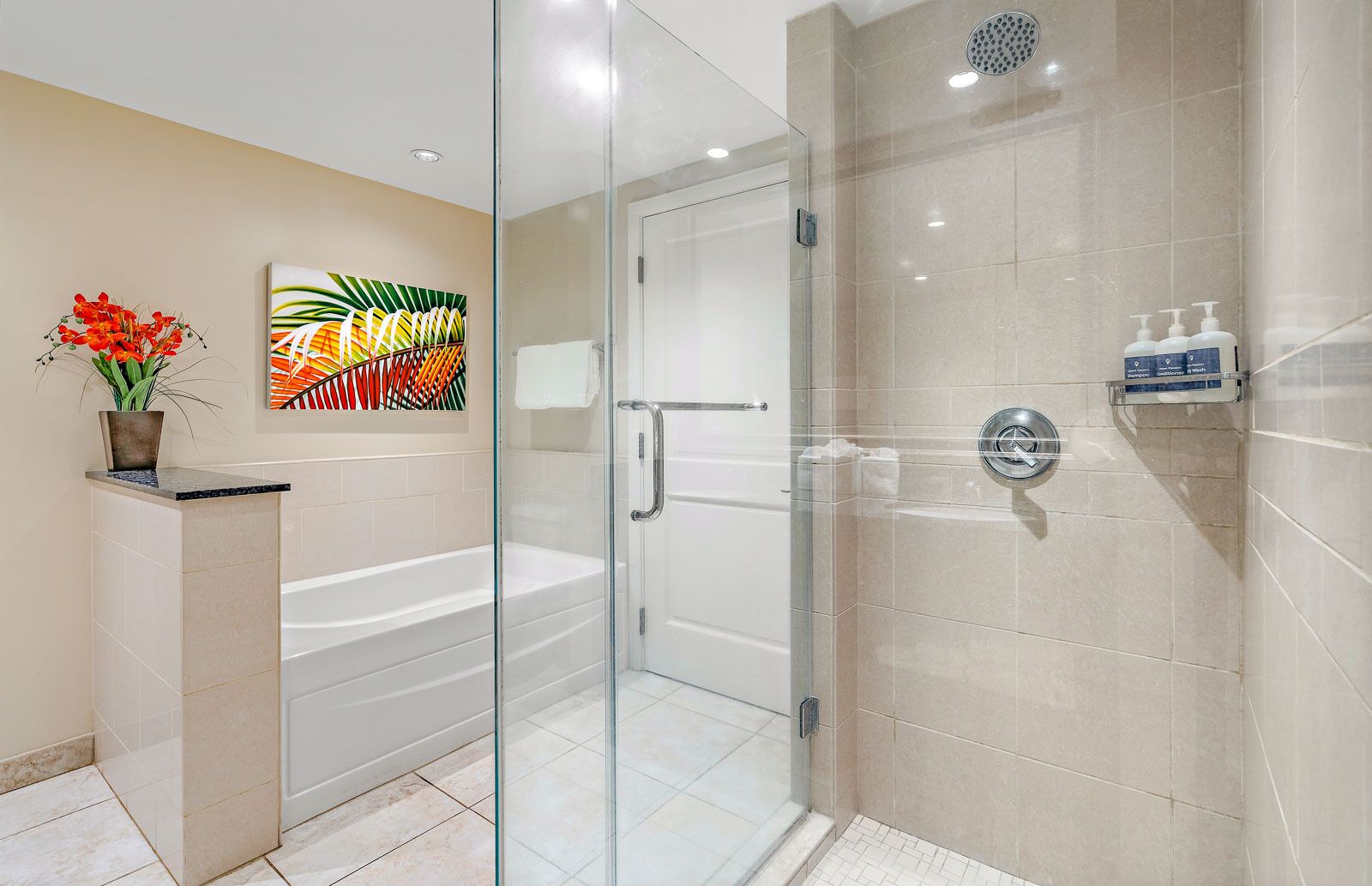 A modern bathroom with a glass-enclosed shower, a white bathtub, and a beige tiled wall.