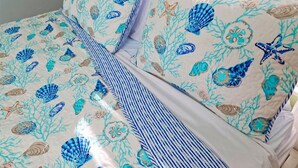 A bed with a striped bedspread and pillows featuring a sea-themed pattern.