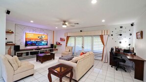 A living room with a TV, sofa, coffee table, and a desk with a chair.