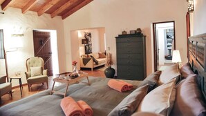 A cozy room with a bed, a sofa, a chair, a dresser, and a small table with a tray.