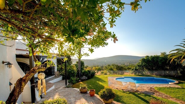 A backyard with a swimming pool, a pergola, and a view of the mountains.