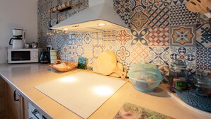 A kitchen with a wooden countertop, a microwave, a coffee maker, and a patterned backsplash.