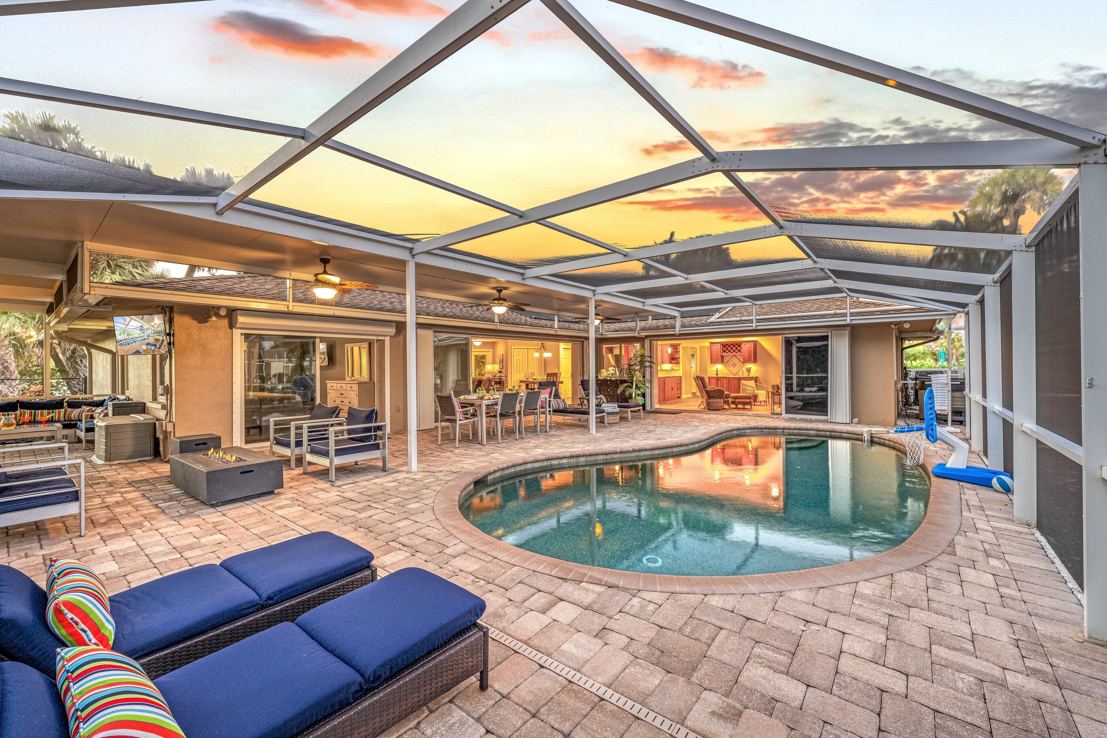 A covered outdoor swimming pool area with lounge chairs and a patio.