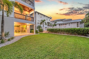 A modern multi-story residential building with a well-maintained lawn and a balcony with outdoor furniture.