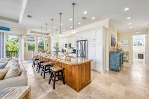 A spacious kitchen with a central island, bar stools, and a dining area with a sofa.