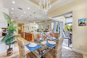 A spacious dining area with a glass table, wicker chairs, and a view of the pool.