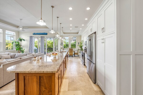 A spacious kitchen with a large island, stainless steel appliances, and a view of the outdoors.