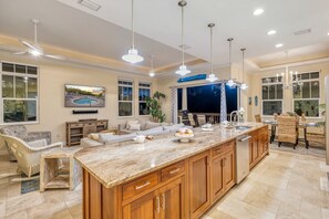 A spacious kitchen with a large island, wooden cabinets, and pendant lighting.