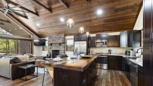 Una cocina moderna con una isla central, electrodomésticos integrados y una chimenea de piedra.