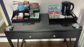 A hotel desk with a glass top, featuring a tray with toiletries, a coffee maker, and water bottles. - Brighouse Studio - Pet Friendly! - Free Parking (Brighouse)