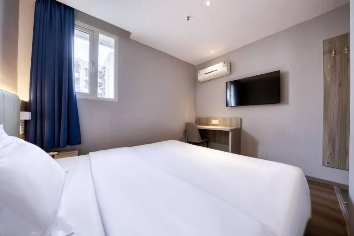 Une chambre d’hôtel dotée d’un grand lit, d’un bureau, d’un téléviseur à écran plat fixé au mur et d’un appareil de climatisation.